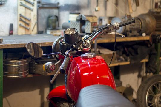 Part of red vintage motorcycle parked in the garage, close-up