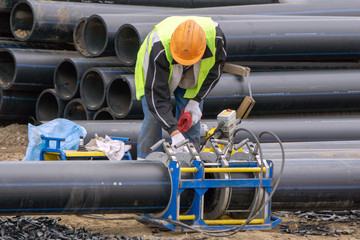 Khimki, Russia - June 13, 2018: Worker at the construction site makes a pipeline