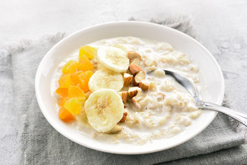 Oats porridge with banana slices, nuts and dried apricot