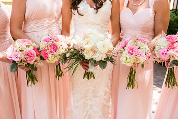 Close up of pink rose bouquets being held by bride standing with her bridesmaids