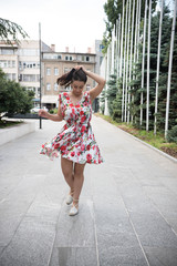 young beautiful woman in colorful dress dancing on street 