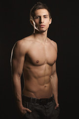 Fototapeta premium Shirtless, fitness shaped muscular men with perfect sporty body only in jeans with arms in a pockets posing at black background