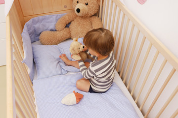 Ein zweijähriger Junge in seinem Kinderbett