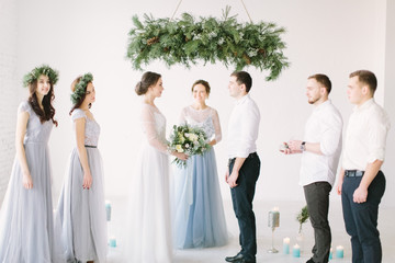 Bride and groom during wedding ceremony indoors. Ceremony master performing speech. Bridesmaids and groommen are smiling and happy