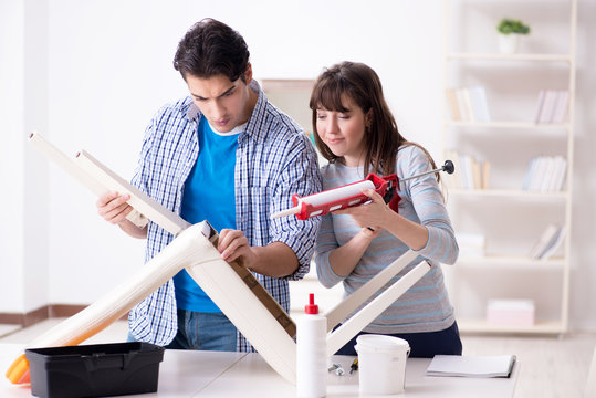 Wife helping husband to repair broken chair at home - Powered by Adobe
