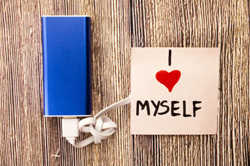 A blue energy storage device and statement about himself I LOVE Myself is present on a woody object.This picture is telling about loving himself or self love