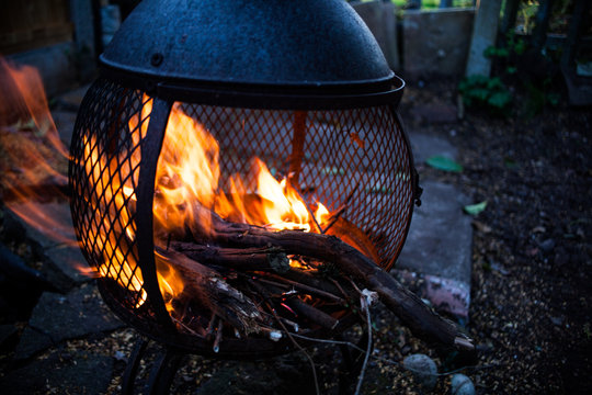 Closeup view on open fire flames. Burning bonfire in the metal housing heater. Campfire in motion image. Frozen image of blaze. Dark mood photo with charring.