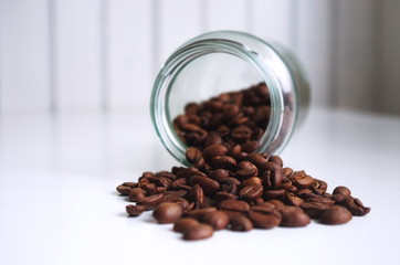 Spilled coffee beans from glass jar on kitchen table. its coffee time. Espresso drink. 