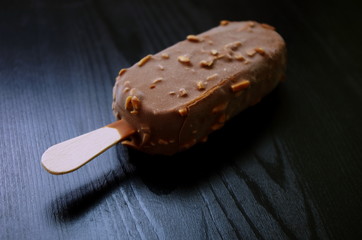 Chocolate ice lolly with almonds on the wooden vintage table. Ice cream bar,summer hot day. Cold yummy ice cream .Ice cream concept.