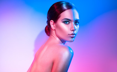 High fashion model girl in colorful bright sparkles and neon lights posing in studio. Portrait of...