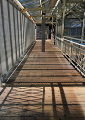 Shadows of railings reflect onto wooden floor of Chicago's Adams/Wabash el train station platform.