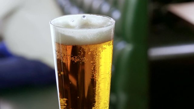 Close-up shot of one glass of beer standing on bar counter in a modern pub. 4K