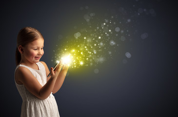 Little cute girl playing on sparkling tablet
