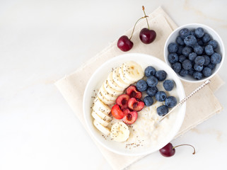 Large bowl of tasty and healthy oatmeal with fruits and berry for Breakfast, morning meal. Top view, copy space