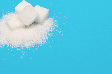 White sugar in cubes on a blue background. An empty place to write a text.