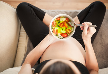 Pregnant mother eating healthy salad. 