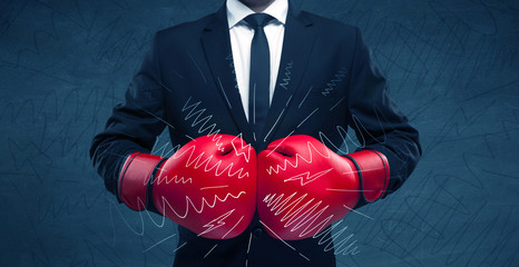 A confident businessman standing in red boxing gloves on his hand in front of blue wall background with drawn strength lines illustration concept.