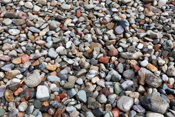 Background made of little stones on the beach. Colorful stones on the seashore. Abstract background with nature stones. Decoration made of colorful stones.