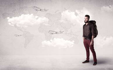Handsome young man standing with a backpack on his back and planes in front of a world map as a background 