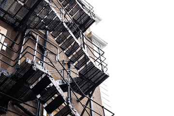 Metal construction on the building. Fire stairs on the old building. Frog perspective on the large old building with metal stairs. Building made of bricks. © A