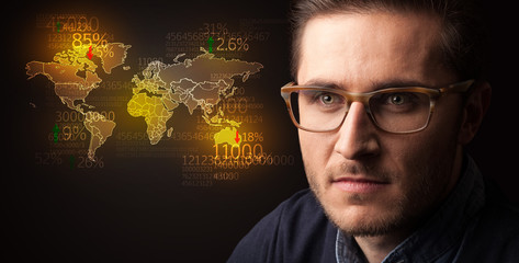 Portrait of a young businessman with a world map and numbers next to him on a dark background