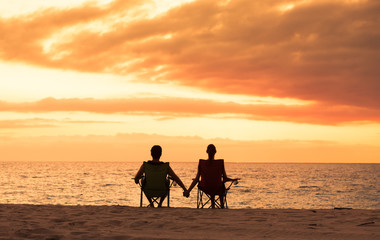 Fototapeta na wymiar Couple sitting at the beach holding hands. 