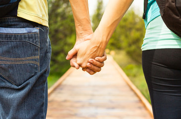 Couple holding hands walking down path. 