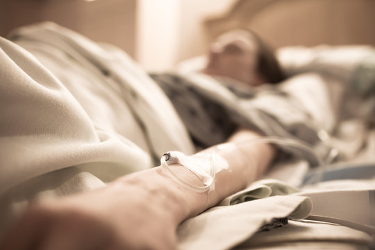 Unrecognizable sick woman lying in hospital bed. 