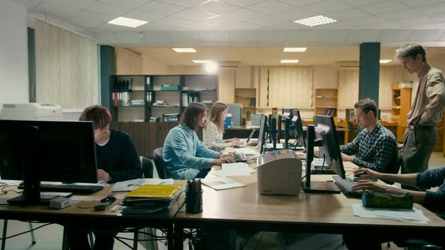 Young Employees are Working in the Open Space Office at Common Desk with Computers