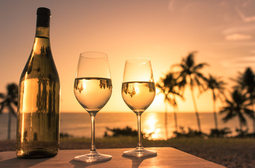 Romantic, and relaxing beach holiday for two background. Pair of wine glasses on the beach at sunset. 