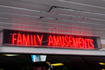 Family amusements sign on the street. Leisure concept with neon lights sign. Advertisement with neon lights on the street. Amusement park advertisement neon light.