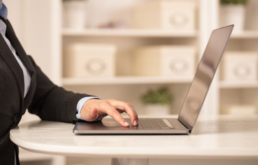 Business woman below chest working on her laptop in a cozy environment
