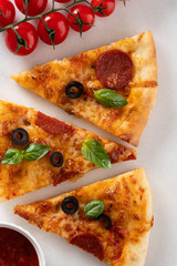 Cut into slices delicious fresh pizza with  pepperoni on a white background. Top view. Pizza on the white table.