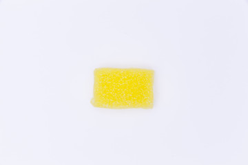 A soft sugar candy in the shape of a rectangle. Yellow on white. Isolated studio shot.
