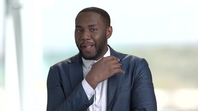 Playful afro-american entrepreneur. Portrait of sexy stylish dark-skinned businessman on blurred background.