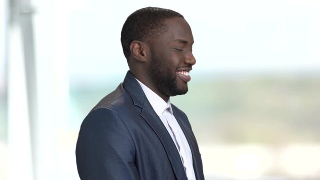 Portrait of smiling afro-american businessman. Flirtatious dark-skinned guy in business suit on blurred background.