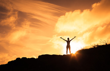 Female standing on a mountain with her arms up in the air. Happiness, motivation and feeling good...