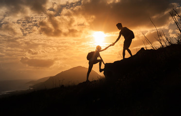People helping each other up a mountain. Adventure, taking risk,  and teamwork concept. 