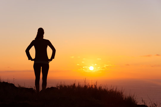 It's a new day concept. Young female standing watching the sunrise. 