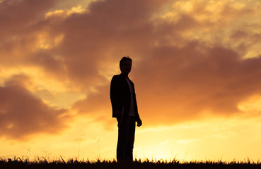Silhouette of man standing against sunset. 