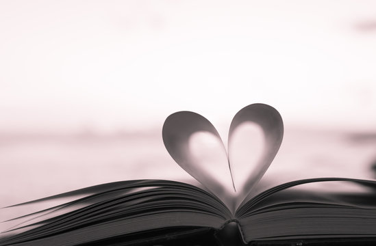 Close up heart shape from paper book on sand in the beach with vintage filter blur background
