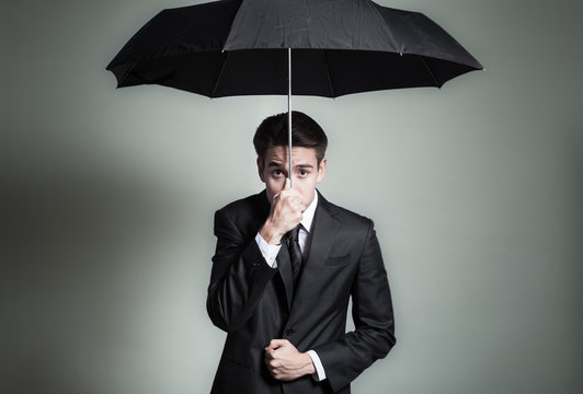 Expressive Man In Suit Holding Umbrella Over Head.  