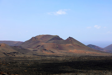Fototapeta na wymiar Red mountains and volcanic black land in Lanzarote Island looking like martian landscape, Canary Islands, Spain