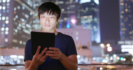 Asian Man use of tablet computer at night