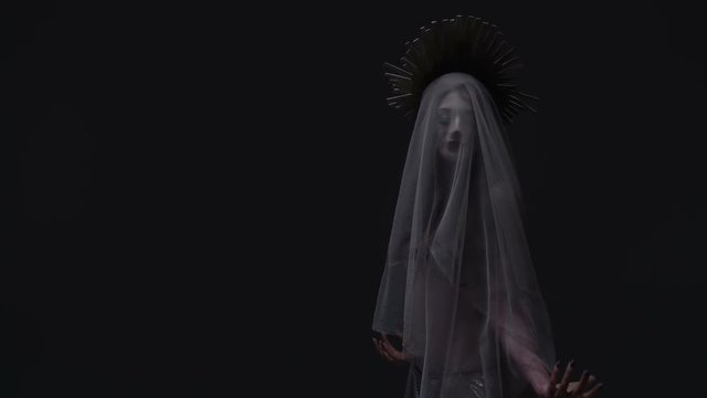 Woman in white crowned veil is standing
