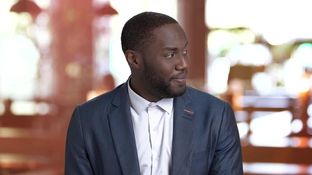 Macho-man looking at a girl passing by. Flirtatious afro-american man in business suit on blurred background. Glint in eyes. Glance of macho-man.