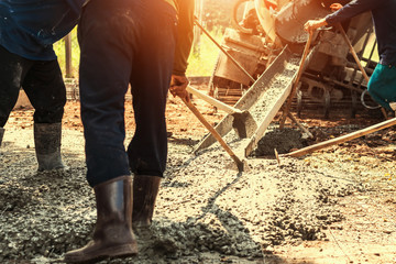 pouring concrete with worker mix cement for building road at construction site