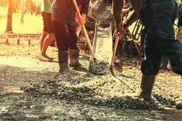 pouring concrete with worker mix cement for building road at construction site