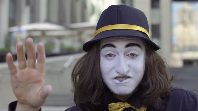 Mime in hat and yellow bow tie fooling around on camera