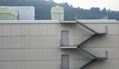 Naklejka premium Stair fire escape and Pipeline water at industrial building wall.